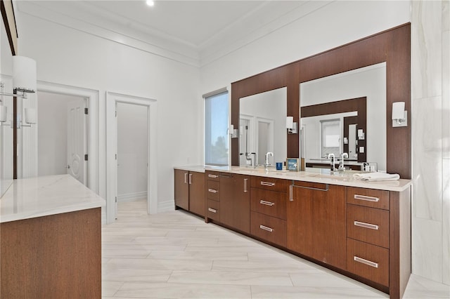 full bath with a sink, crown molding, baseboards, and double vanity