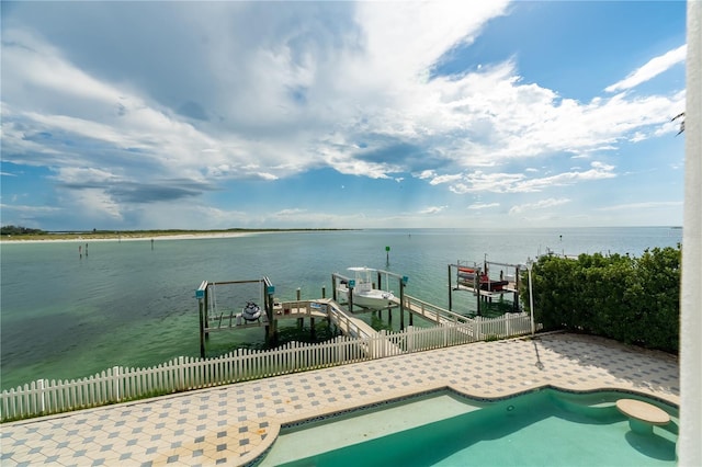 view of swimming pool featuring a dock, a water view, fence, and boat lift