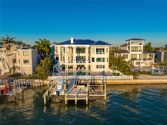 view of dock with a water view, a balcony, boat lift, and a patio