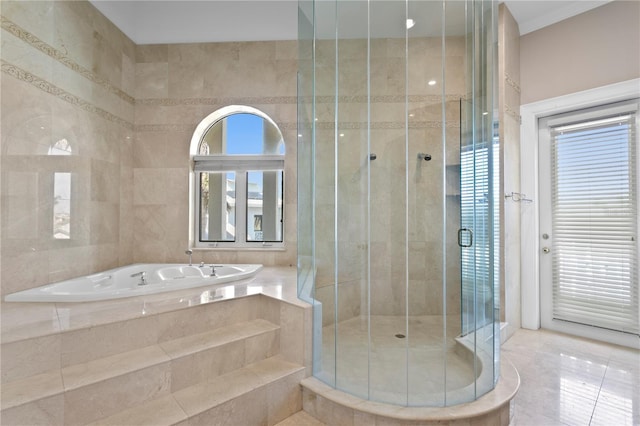 bathroom with a wealth of natural light, tile walls, a garden tub, and a shower stall