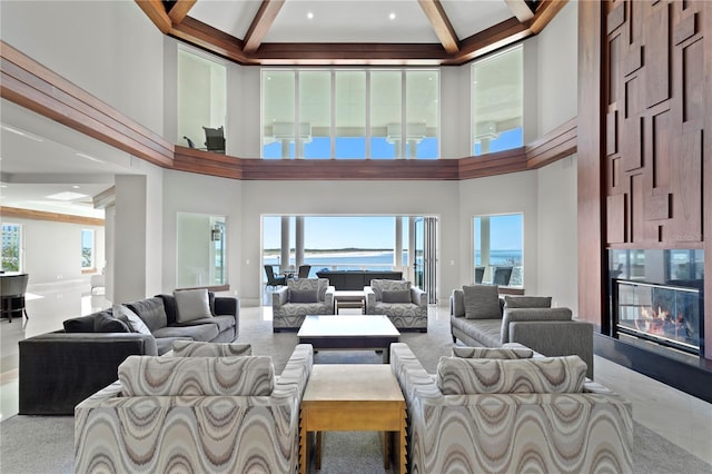 living room with a glass covered fireplace, beamed ceiling, and a towering ceiling