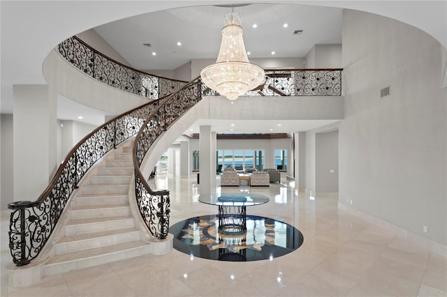 stairway with marble finish floor, recessed lighting, visible vents, a towering ceiling, and a chandelier