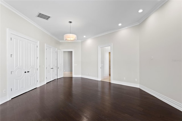 spare room with baseboards, visible vents, wood finished floors, and ornamental molding