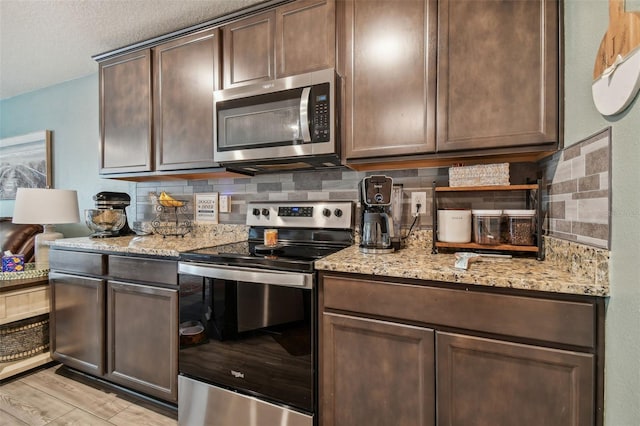 kitchen with tasteful backsplash, appliances with stainless steel finishes, light stone counters, and dark brown cabinets