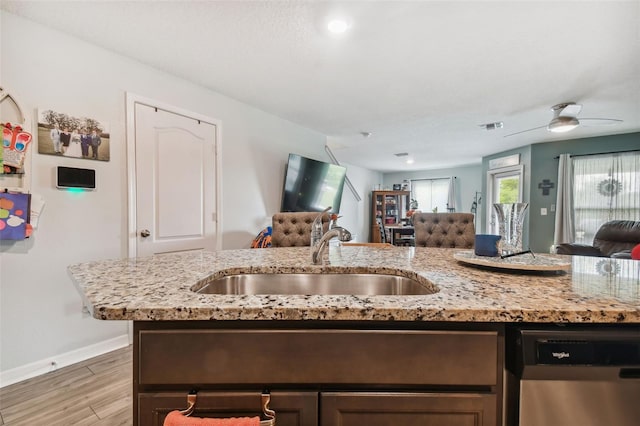 kitchen featuring ceiling fan, stainless steel dishwasher, sink, and light stone countertops