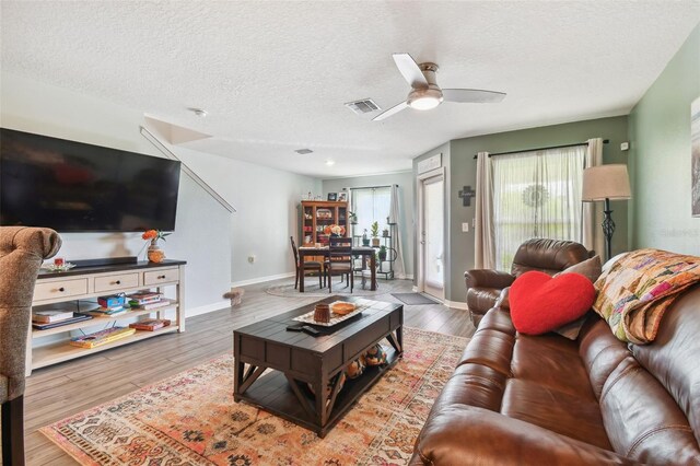 living room featuring ceiling fan, a textured ceiling, and light hardwood / wood-style floors