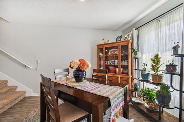 dining room featuring dark wood-type flooring and a textured ceiling