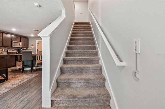 stairway with wood-type flooring and a textured ceiling