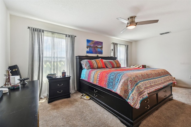 bedroom with ceiling fan, light colored carpet, and multiple windows