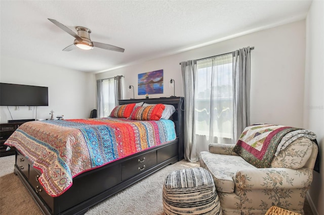 bedroom with multiple windows, a textured ceiling, light colored carpet, and ceiling fan