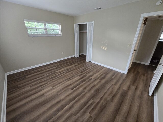 unfurnished bedroom with a closet and dark hardwood / wood-style flooring