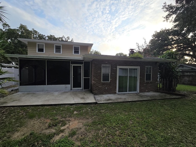 rear view of property with a sunroom, a patio area, and a yard