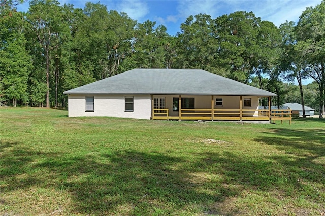 rear view of property featuring a lawn and a deck