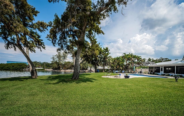 exterior space with a lawn, a water view, and a pool