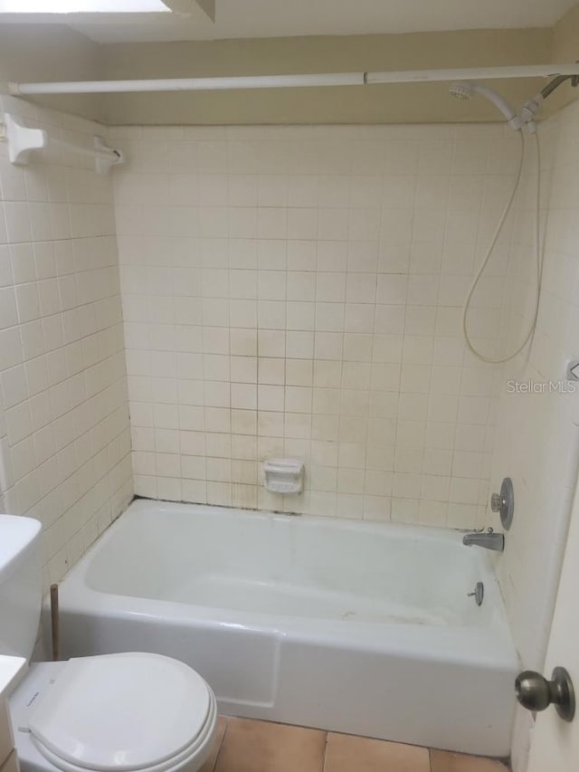 bathroom featuring toilet, tile patterned flooring, and tiled shower / bath combo