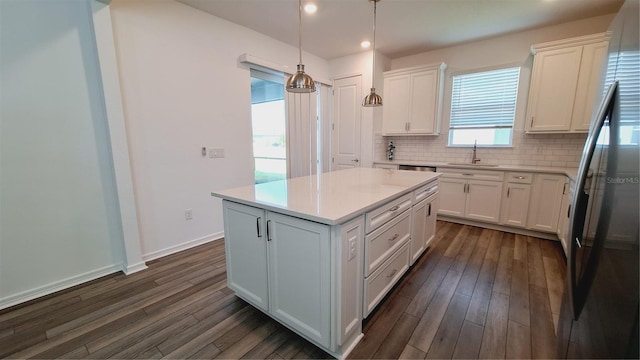 kitchen with a center island, hanging light fixtures, dark hardwood / wood-style flooring, decorative backsplash, and white cabinets