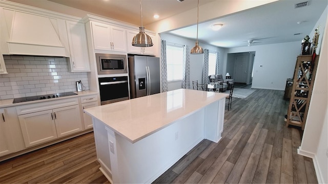 kitchen featuring decorative backsplash, black appliances, custom range hood, and dark wood-type flooring