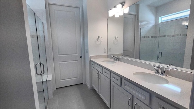 bathroom featuring tile patterned flooring, a shower stall, double vanity, and a sink