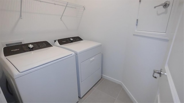 clothes washing area with laundry area, light tile patterned floors, baseboards, and washer and clothes dryer