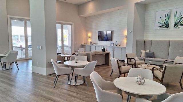 dining area with baseboards, light wood-style flooring, a towering ceiling, and wood walls