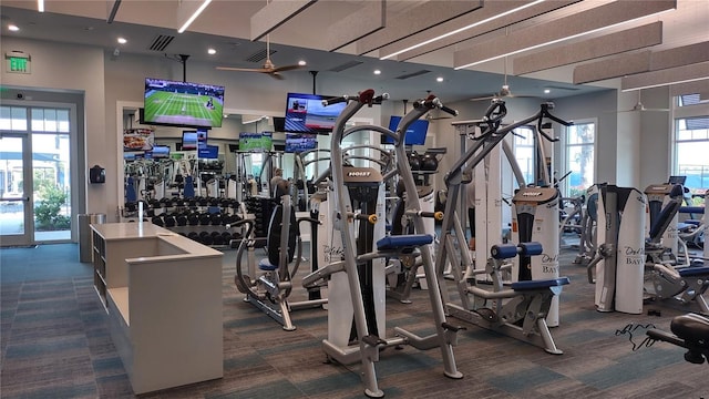 workout area with visible vents, dark colored carpet, and a wealth of natural light