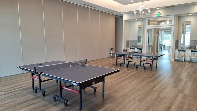 recreation room featuring a chandelier, recessed lighting, light wood-style flooring, and a high ceiling