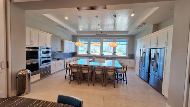 kitchen featuring tasteful backsplash, visible vents, a breakfast bar, a tray ceiling, and high end refrigerator