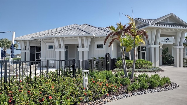 view of front of property featuring metal roof, board and batten siding, driveway, and fence