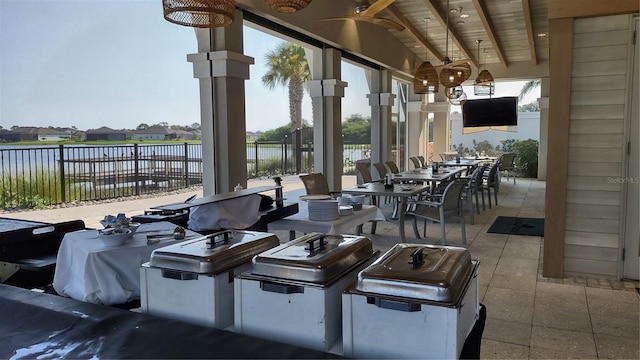 view of patio / terrace featuring exterior kitchen, outdoor dining area, fence, and a water view