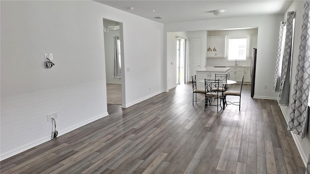 dining space with dark wood finished floors, visible vents, and baseboards