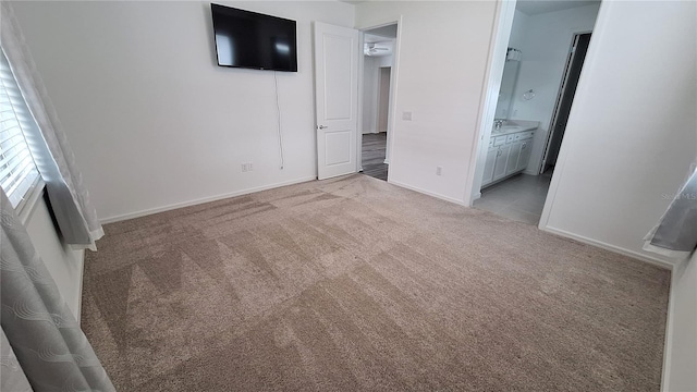 unfurnished bedroom with connected bathroom, baseboards, and light colored carpet