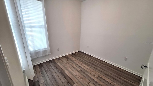 empty room featuring baseboards and dark wood finished floors