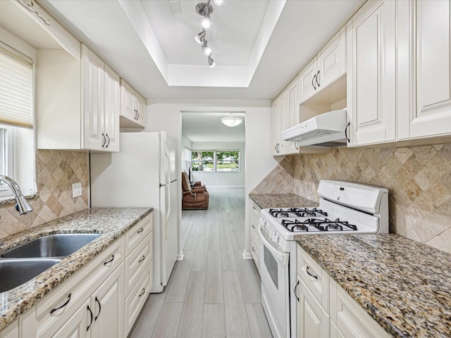 kitchen with white cabinets, a tray ceiling, backsplash, and white appliances