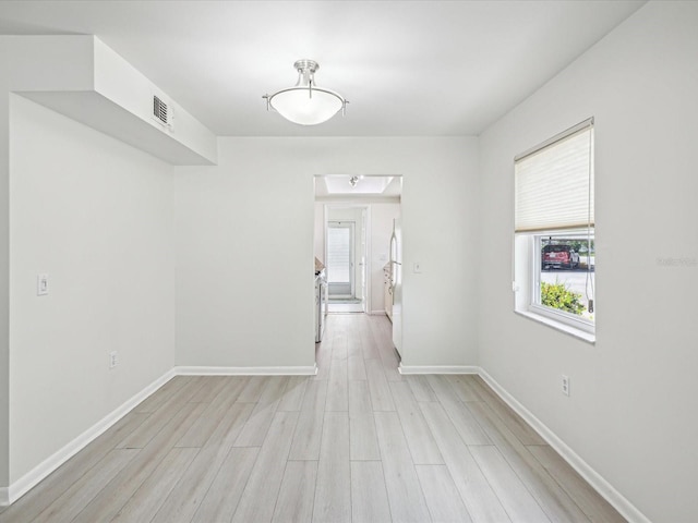 empty room featuring light wood-style flooring, visible vents, and baseboards