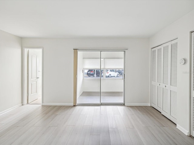 unfurnished bedroom with two closets and light hardwood / wood-style flooring