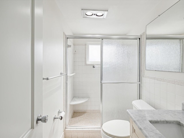 bathroom featuring a shower with shower door, tile walls, toilet, and vanity