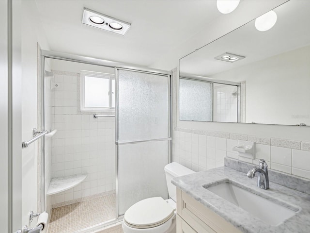 full bathroom featuring a stall shower, vanity, toilet, and tile walls