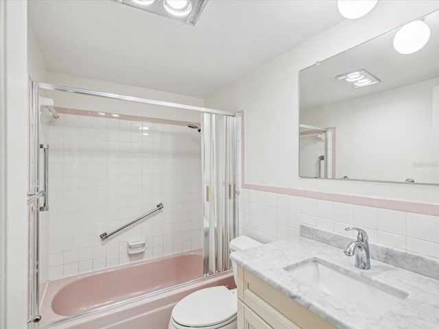 full bathroom featuring decorative backsplash, vanity, bath / shower combo with glass door, tile walls, and toilet