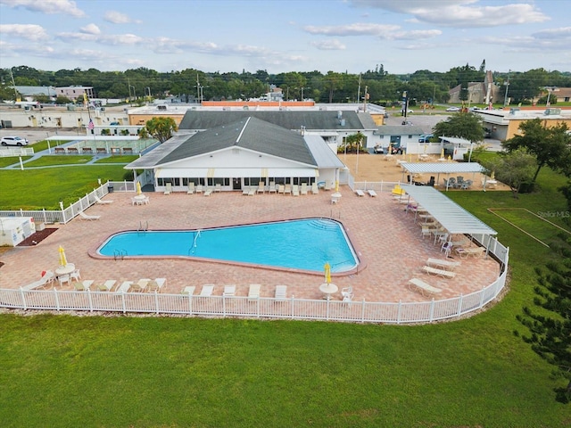 pool with a patio, a lawn, and fence