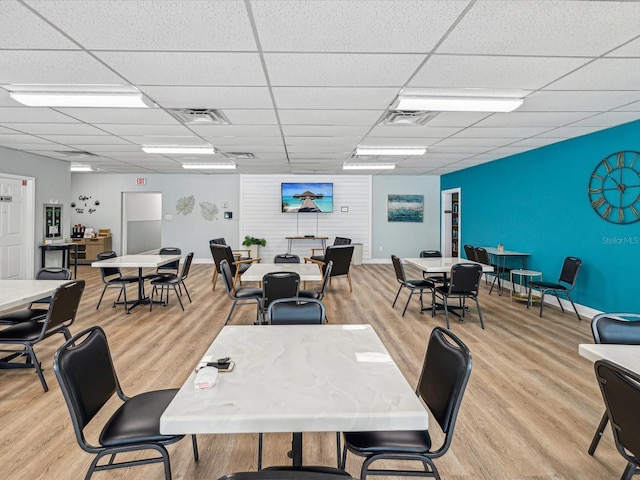 dining area with light hardwood / wood-style flooring and a drop ceiling