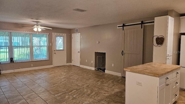 kitchen featuring white cabinetry, a textured ceiling, light tile patterned floors, a barn door, and ceiling fan