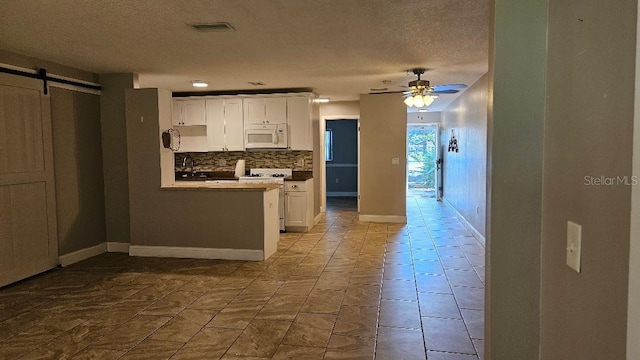 kitchen featuring ceiling fan, backsplash, a barn door, white cabinets, and light tile patterned flooring