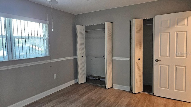 unfurnished bedroom featuring two closets and hardwood / wood-style flooring