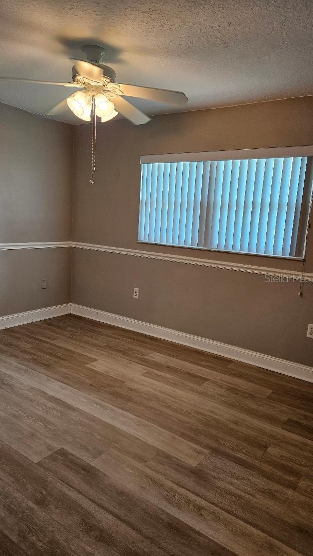 empty room with ceiling fan, a textured ceiling, and hardwood / wood-style floors