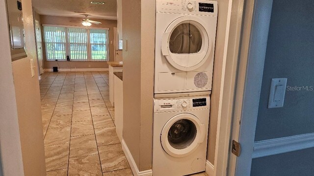 laundry room featuring ceiling fan, stacked washer and clothes dryer, and light tile patterned floors