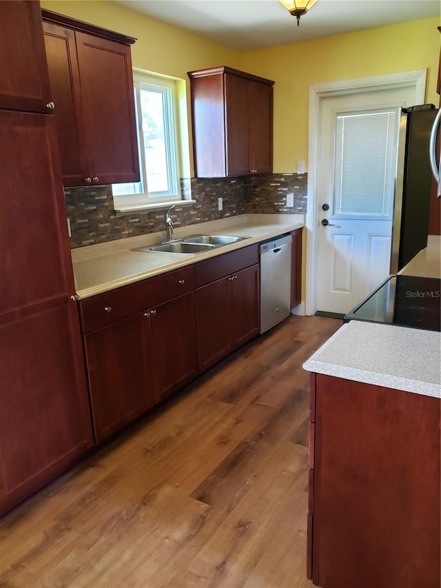 kitchen with tasteful backsplash, sink, wood-type flooring, and appliances with stainless steel finishes