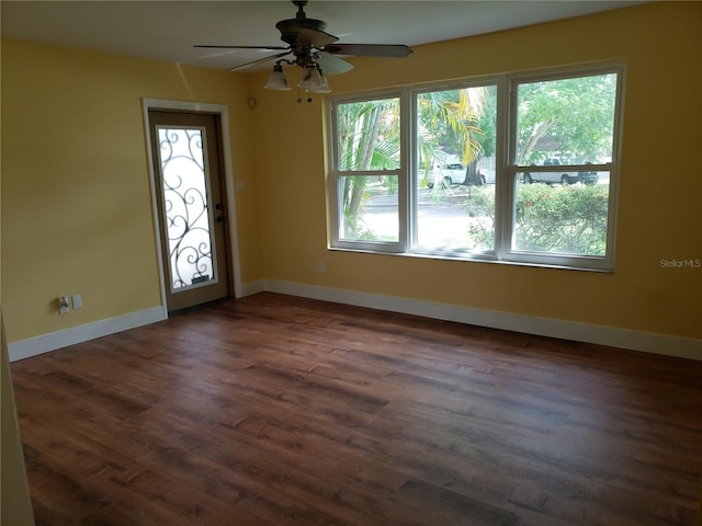 empty room with a wealth of natural light, dark wood-type flooring, and ceiling fan