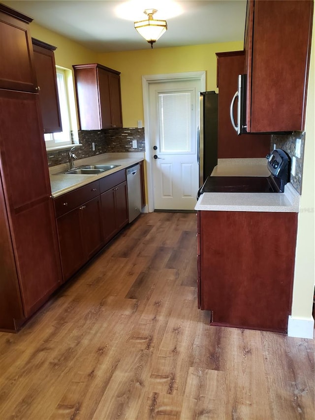 kitchen featuring stainless steel appliances, light hardwood / wood-style flooring, tasteful backsplash, and sink