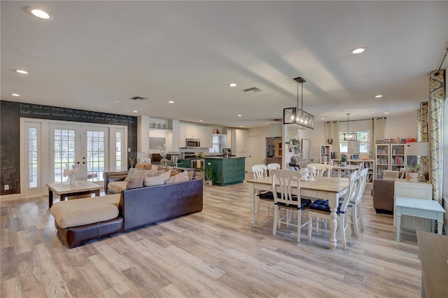 living room with light hardwood / wood-style floors, french doors, and a wealth of natural light