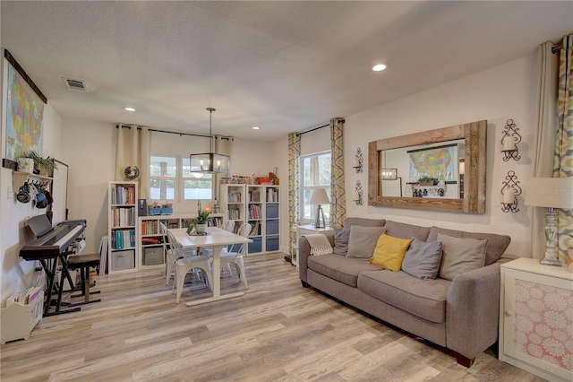 living room with a textured ceiling, a chandelier, and light hardwood / wood-style floors